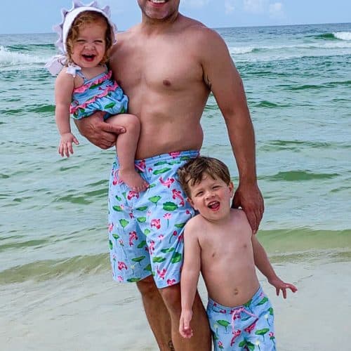 Dad with kids on beach in matching Beaufort Bonnet Company swimsuits